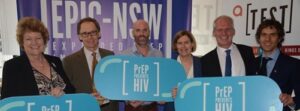 Politicians, researchers, and community representatives at an EPIC-NSW event. The signs they are holding read: ‘PrEP prevents HIV’